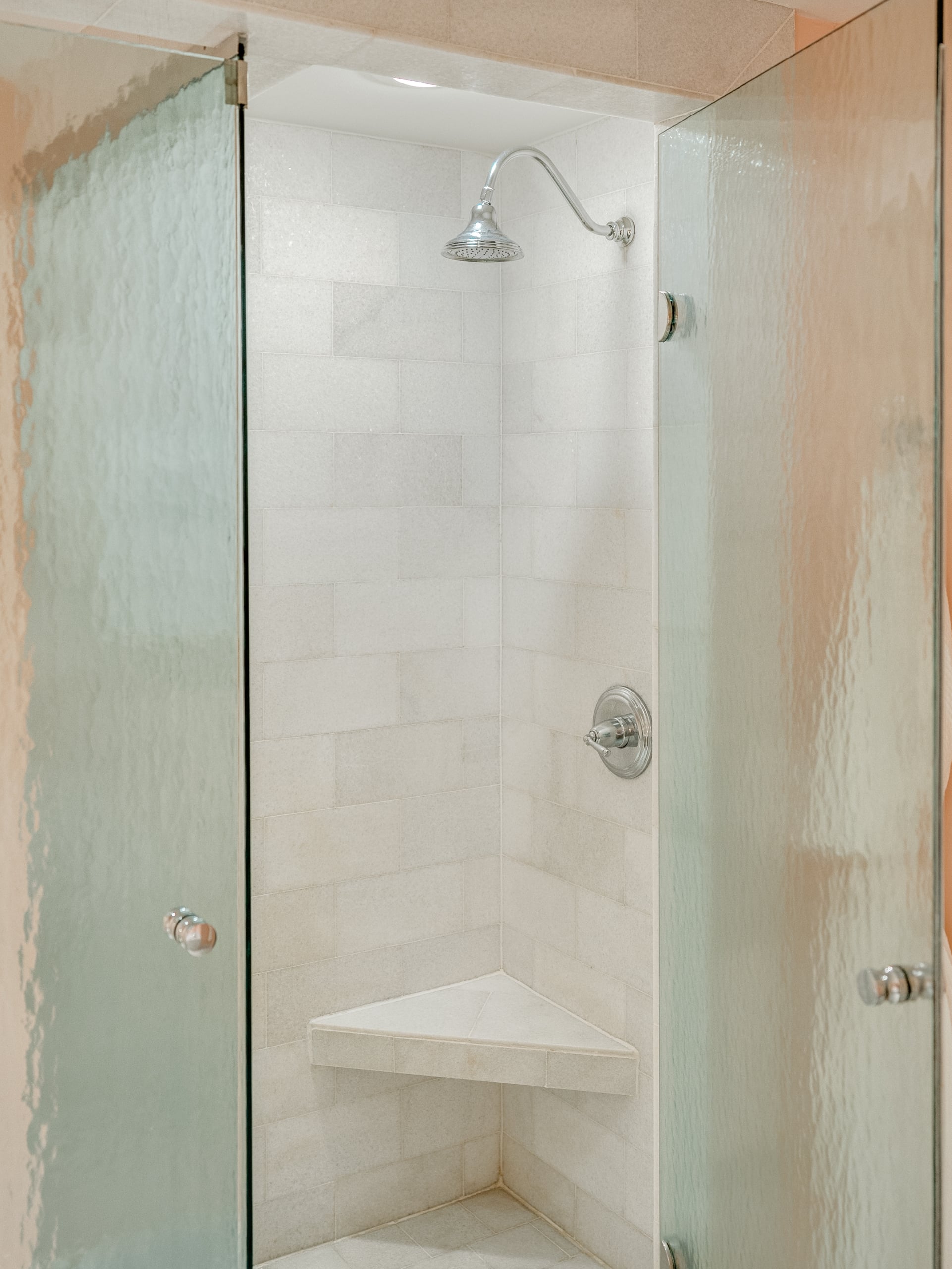 A shower with a glass door and white tiles