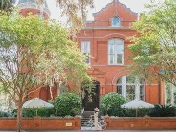A red brick building with white trim and a bicycle in front.