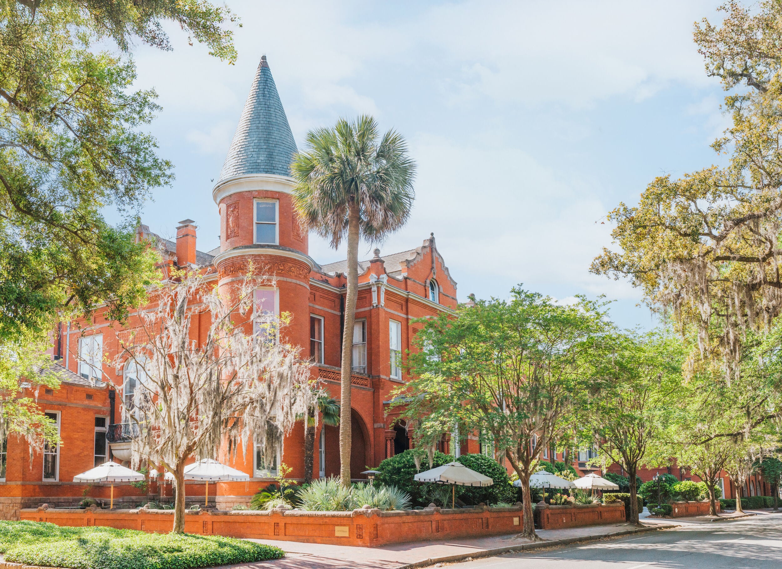 A large red brick building with a tower and trees in front of it.