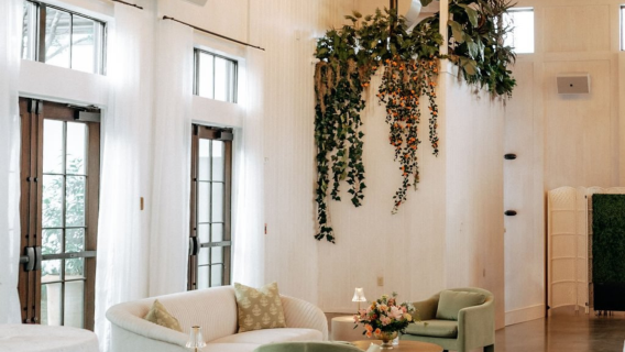 A bright and airy lobby with a high ceiling, large windows, and greenery.