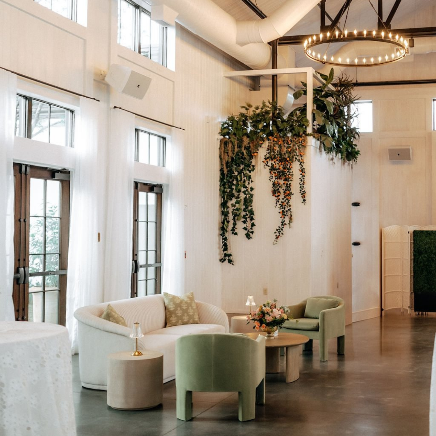 A bright and airy lobby with a high ceiling, large windows, and greenery.