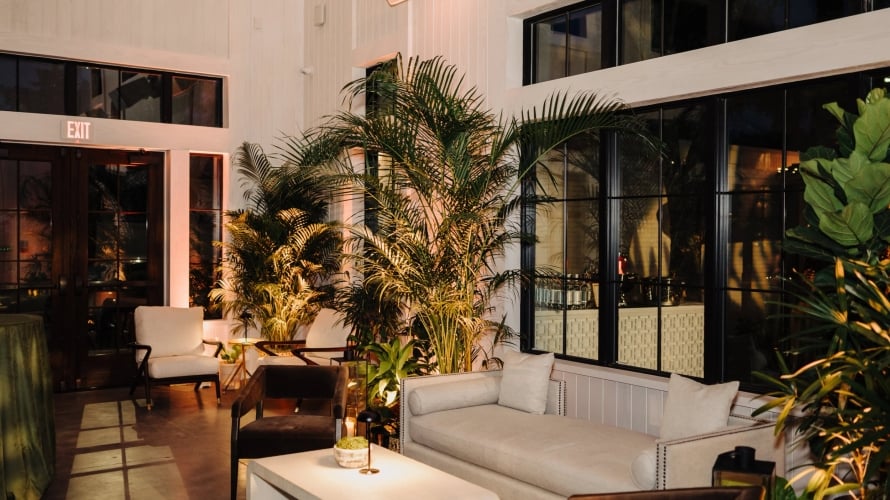 High-ceilinged event space at Hotel Bardo featuring lush indoor palms, white shiplap walls, and warm ambient lighting.