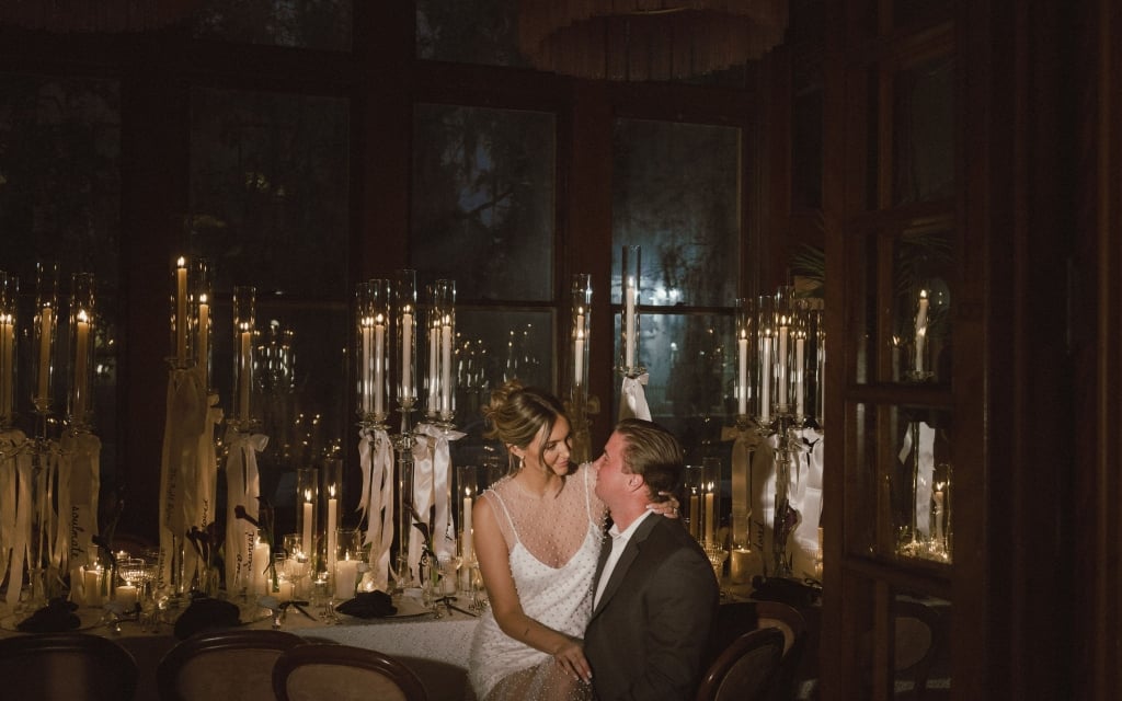 A romantic dinner setting with a couple sitting at a table surrounded by candles.