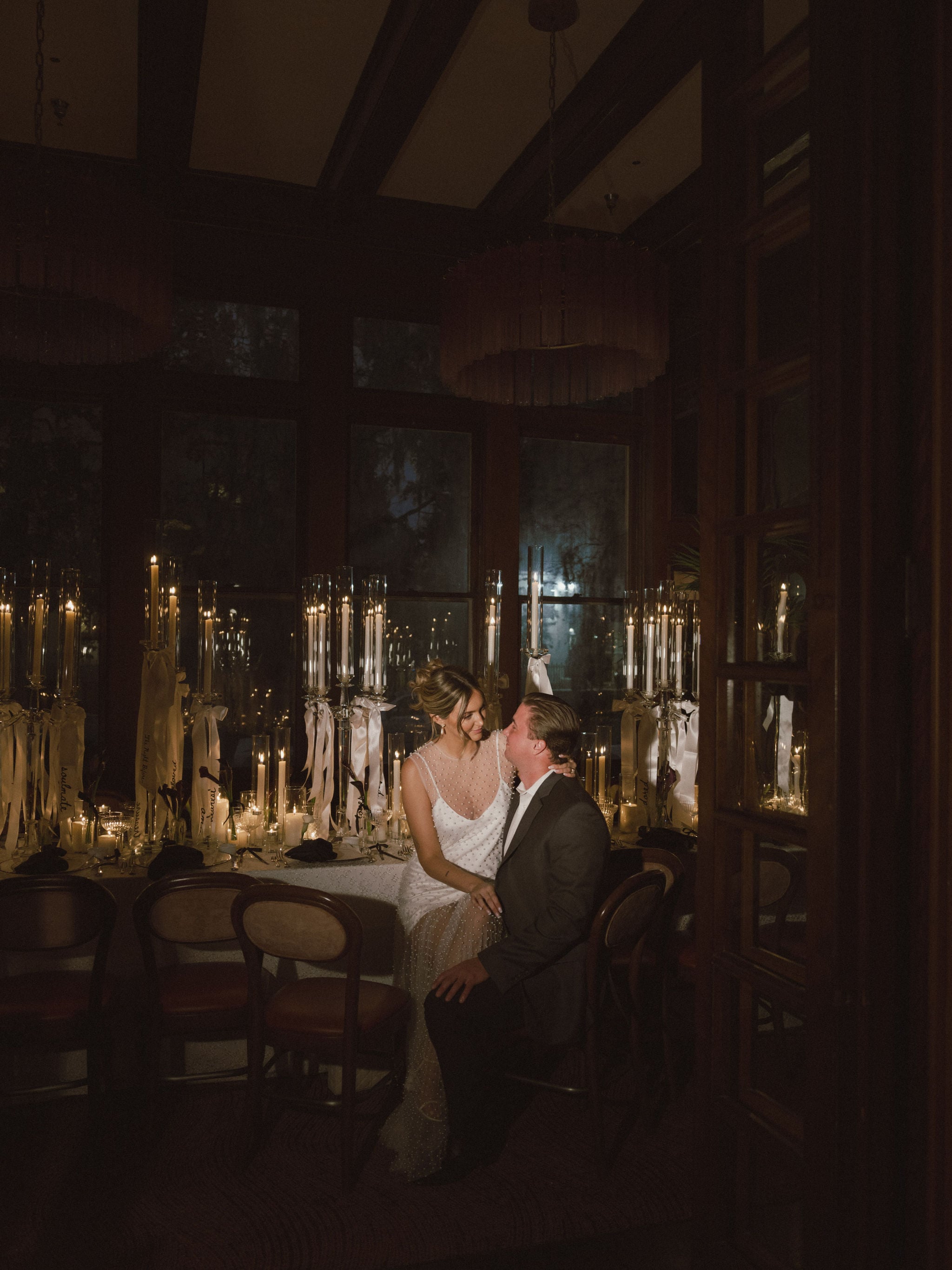 A romantic dinner setting with a couple sitting at a table surrounded by candles.
