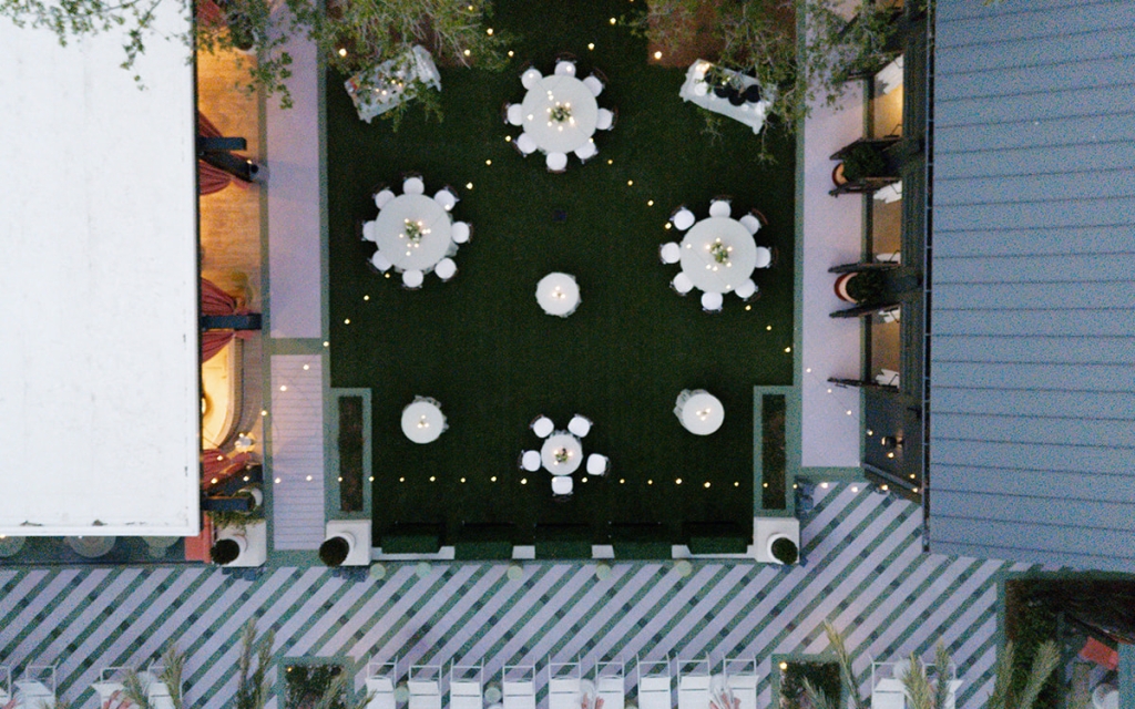 Aerial view of a beautifully set outdoor event space with tables, chairs, and string lights.