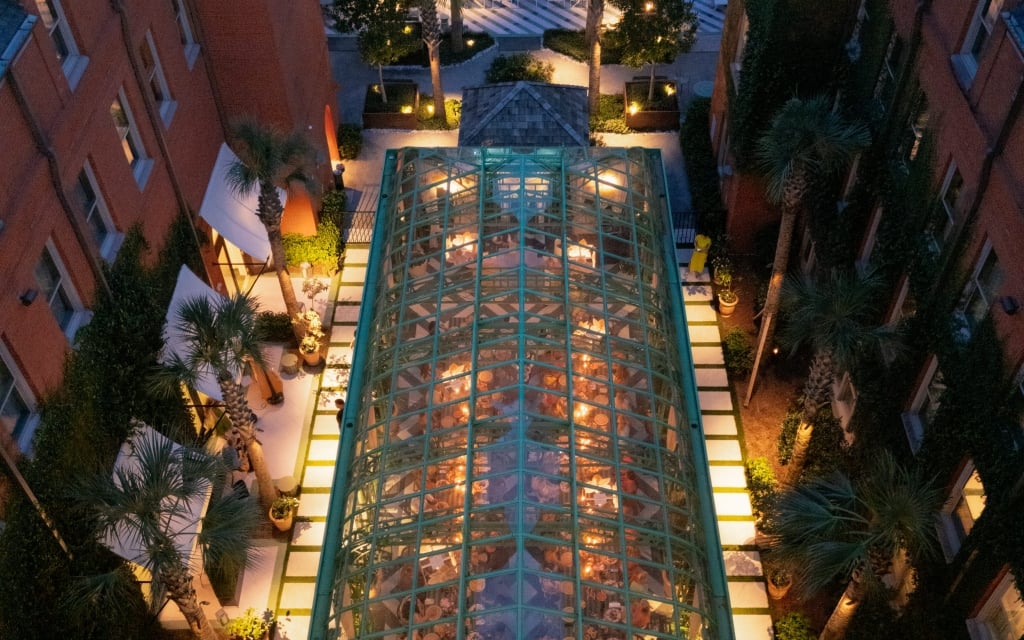 an aerial view of a courtyard with a glass roof and palm trees
