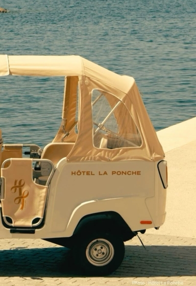 Cream-colored vintage mini vehicle with tan canvas canopy labeled 