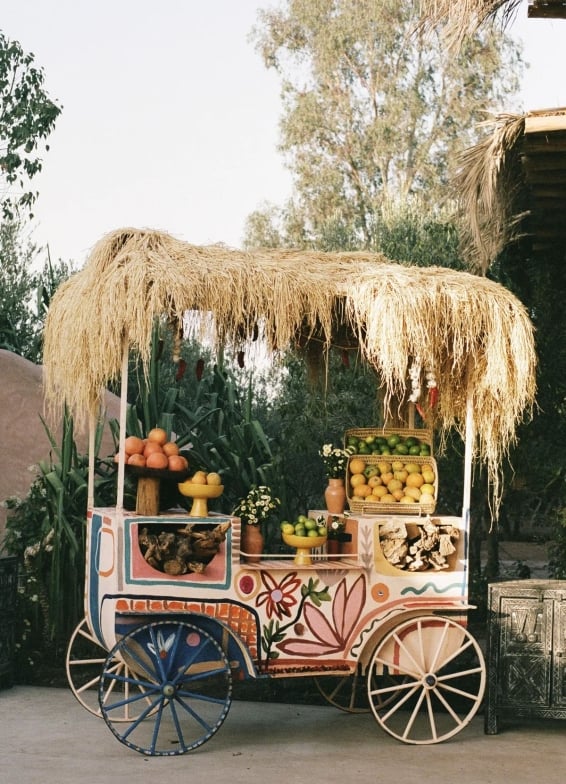 Fresh fruit displayed on a stationary carriage with thatch roof
